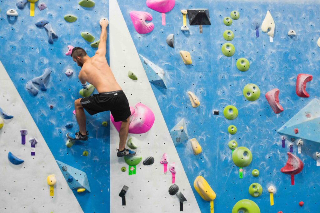 Matthew climbing on a colorful rock climbing wall.
