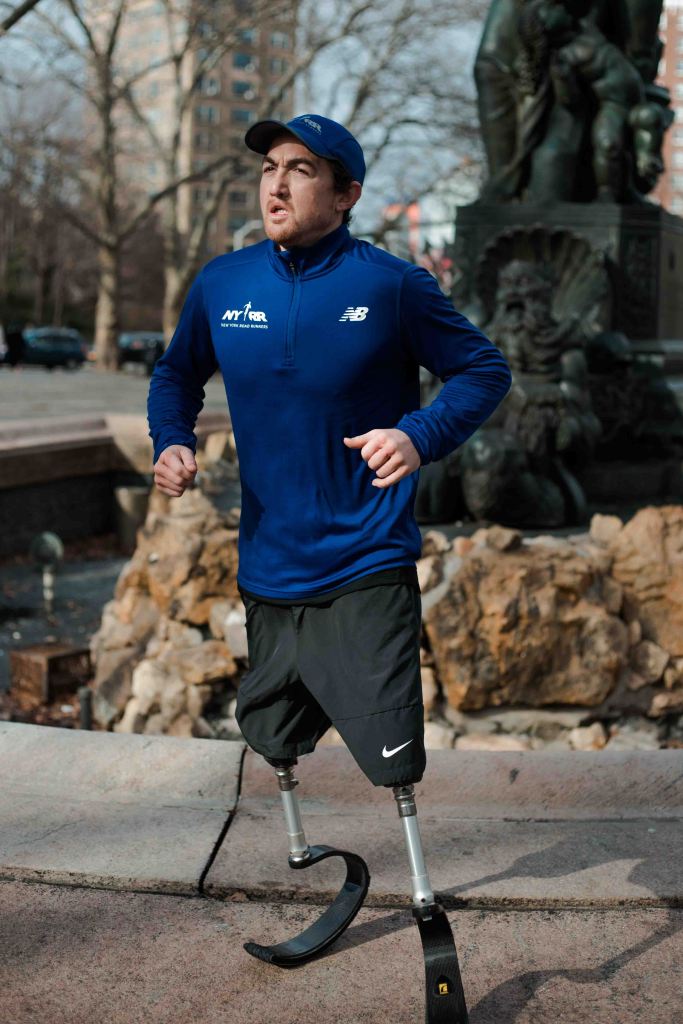 A colour photo of Rudy displaying his prosthetic legs, as he is warming up.